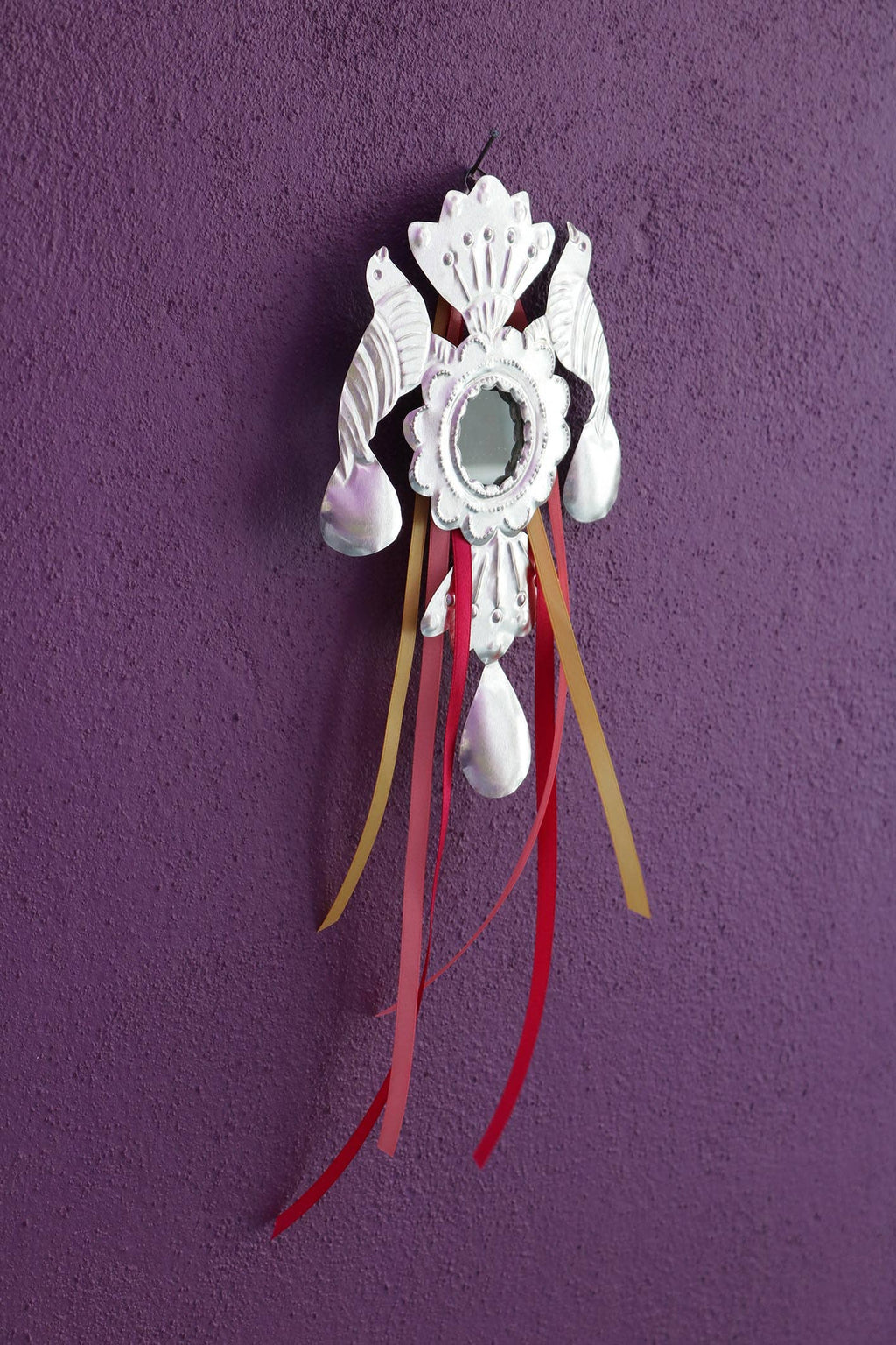Decorative wall hanging with feathers and ribbons on a purple background