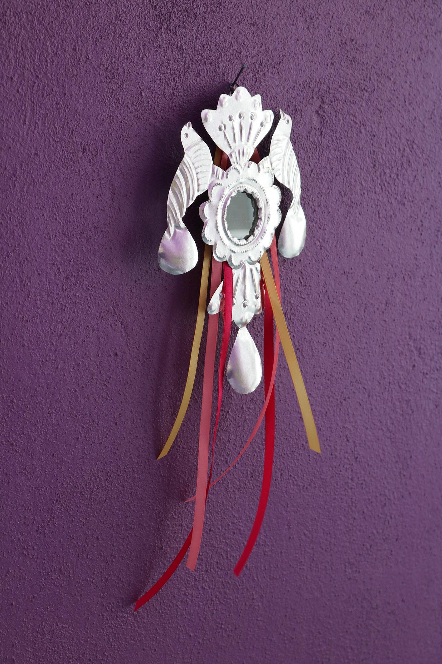 Decorative wall hanging with feathers and ribbons on a purple background